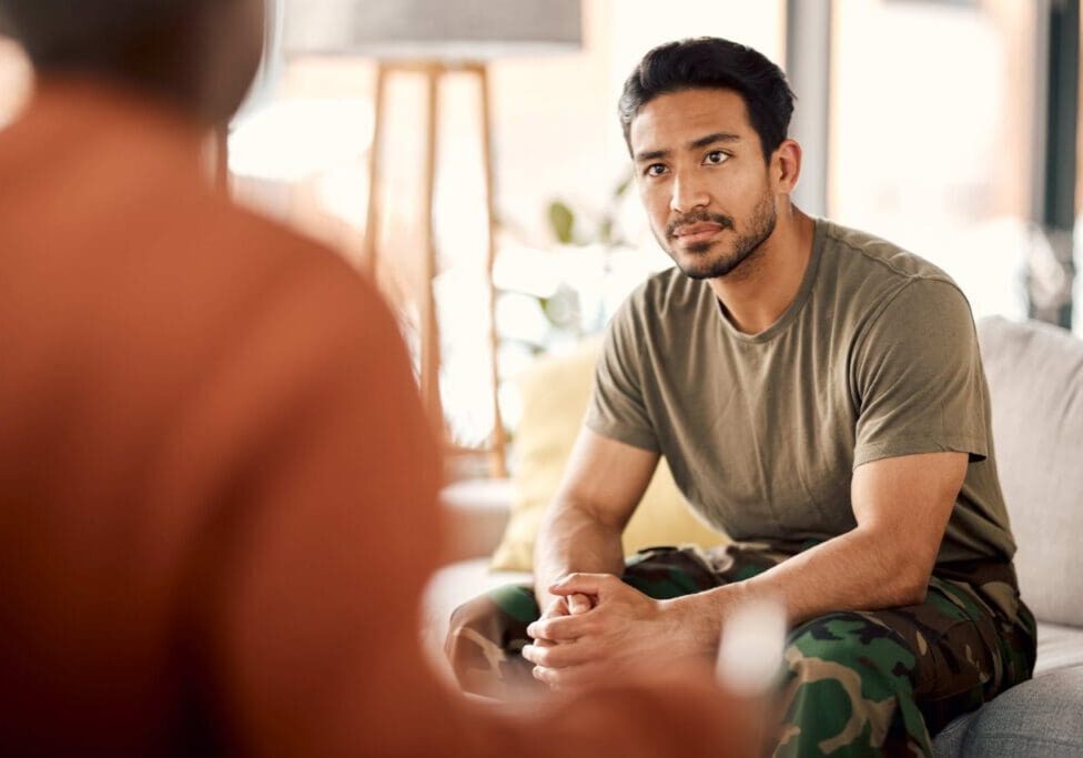 Man in camo pants sitting on couch.